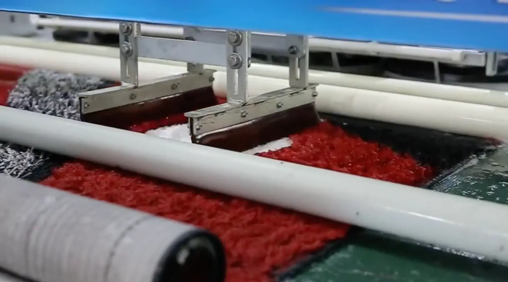 Raclettes évacuant l'eau sale d'un tapis rouge en cours de lavage