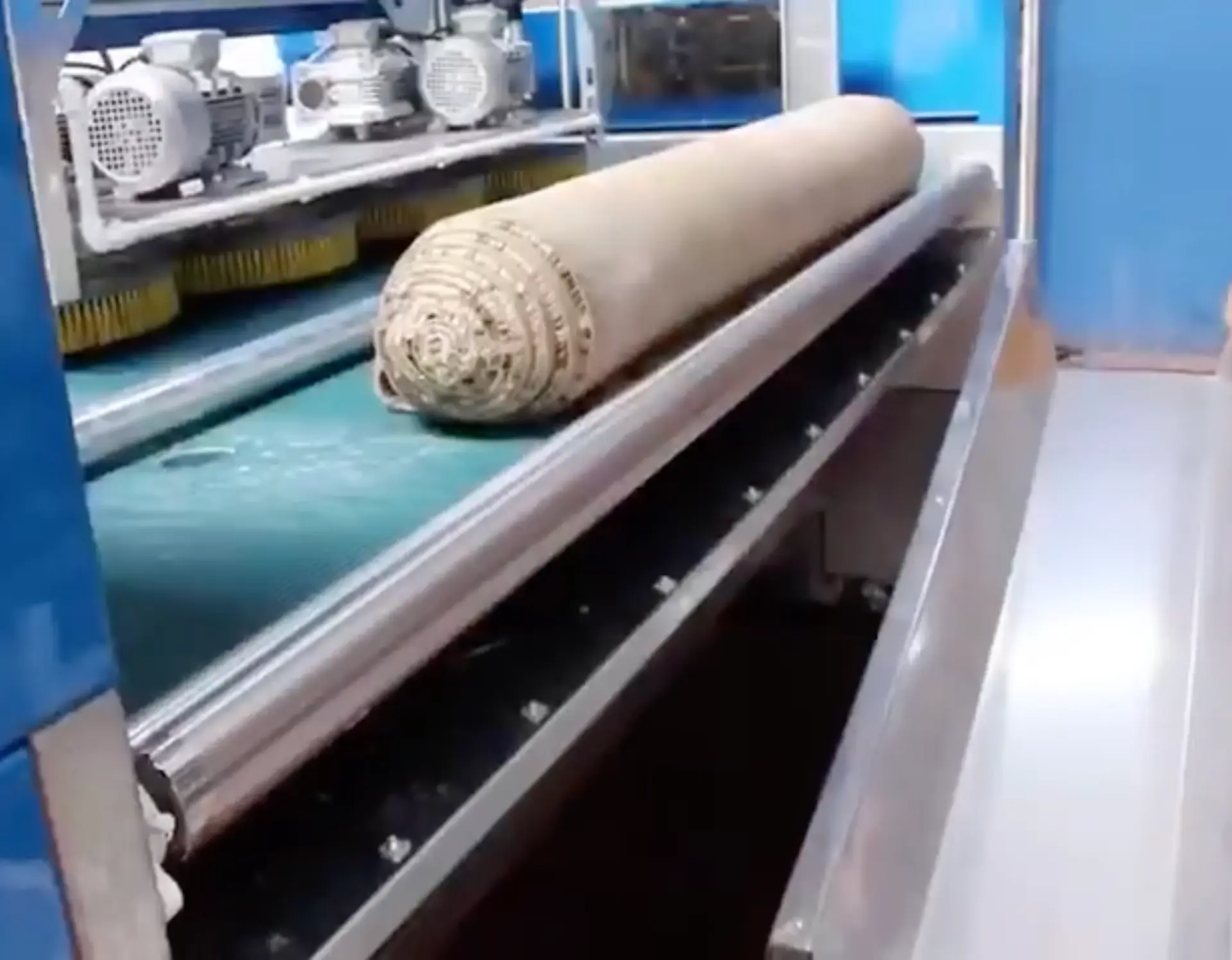 Tapis enroulé sur le convoyeur en sortie de la laveuse industrielle